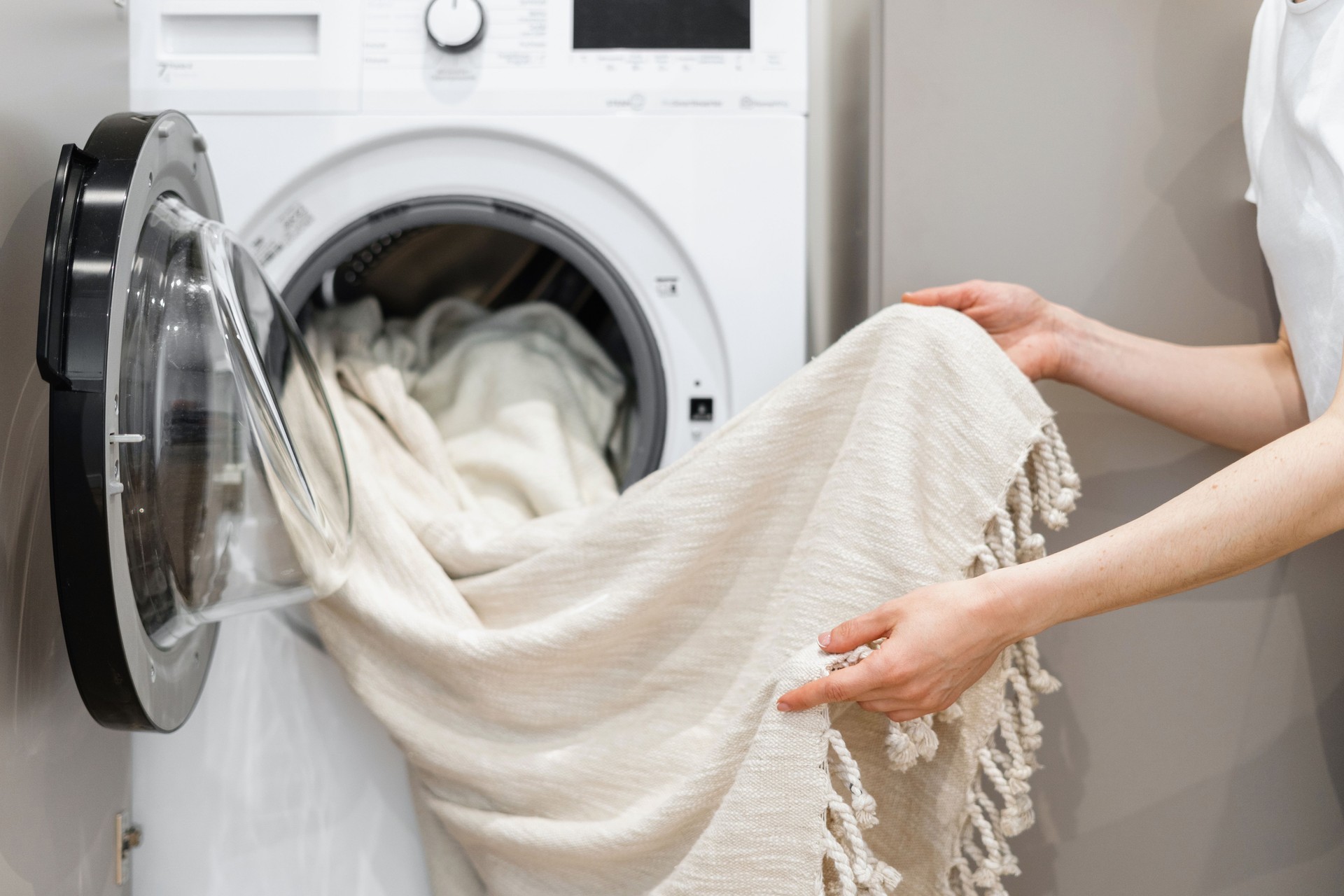 Woman unloading laundry from white washing machine